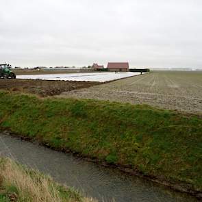 Johan Fase trekt plastic over de aardappelen die hij net heeft gepoot.