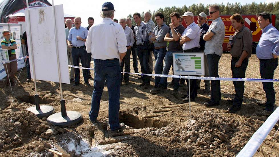 Een groep akkerbouwers luistert op het land naar een uiteenzetting over bandenspanning en de breedte van banden. Met een profielkuil laat Michelin zien dat het effect van de grotere voetprint (bredere band) op de insporing positief is. Verder blijkt dat n