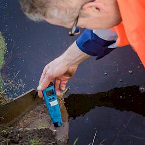 Voor een meting van uitstromende zouten vanaf een varkensbedrijf, steekt Boom een zogeheten geleidbaarheidsmeter in de uitstroomvoorziening. De gemeten waarde van 1.800 mS (microsiemens) valt binnen de toegestane norm.