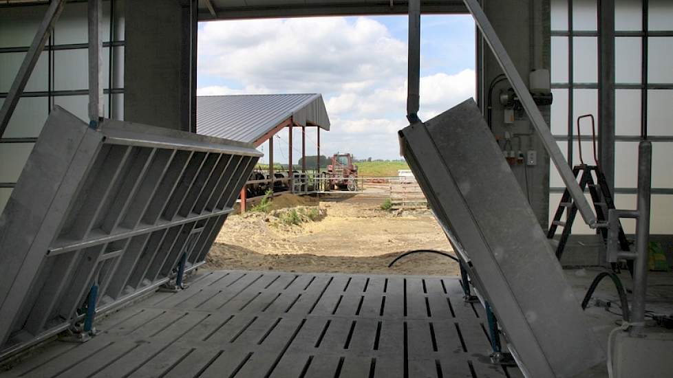 De dieren uit de oude stal lopen via buiten. Twee delen van de voergang worden automatisch opgetrokken (op de foto nog niet geheel omhoog)zodat zich een loopbrug vormt en de voergang schoon blijft.