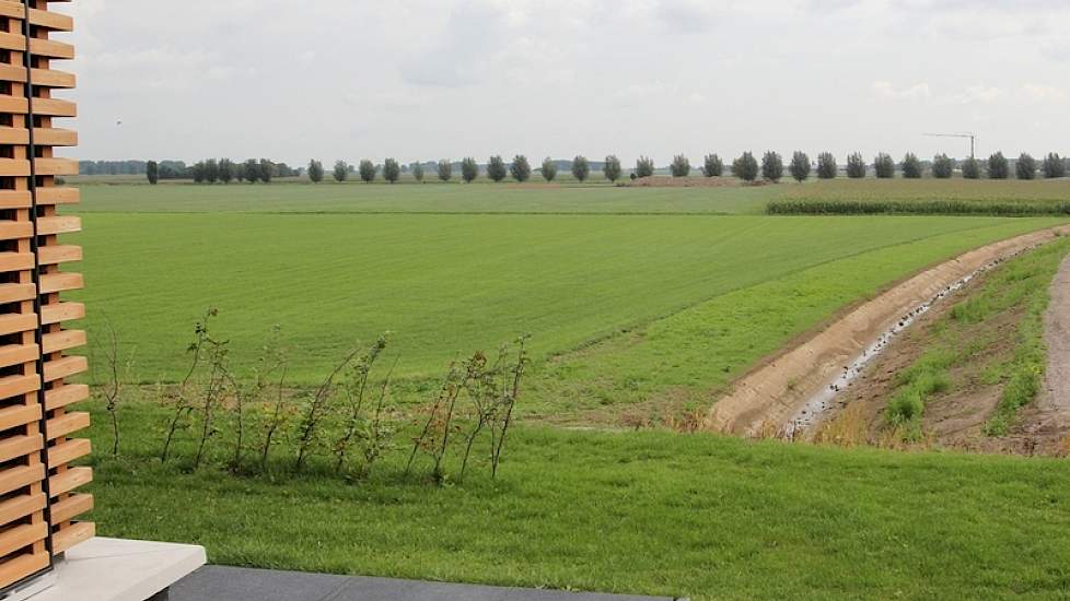 Op de terp staand, valt niet eens op dat het zich op 6 meter hoogte bevindt. Pas aan de randen, zoals hier bij het huis, kijkt men in de diepte. In de verte  de resten van de oorspronkelijke boerderij bij deze terp. Familie Fleerakkers kocht de terp over.